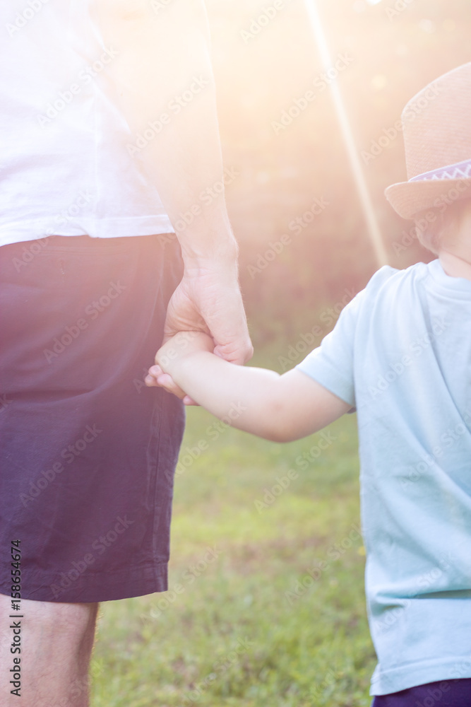 Fototapeta premium Father and son walk at sunset. Happy dad and young son in the Sun.