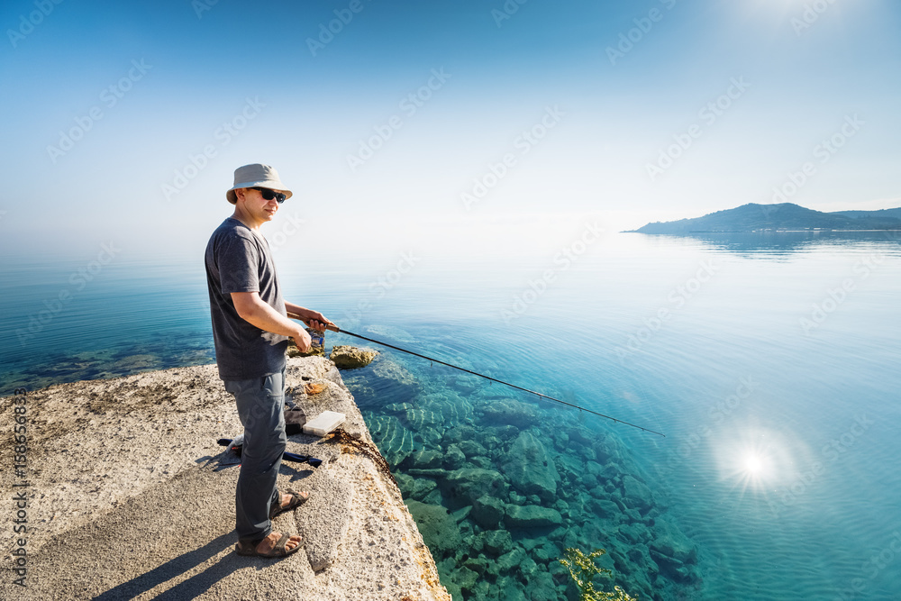 Free Photo  Man holding fishing net and rod standing on wooden pier in  front of lake
