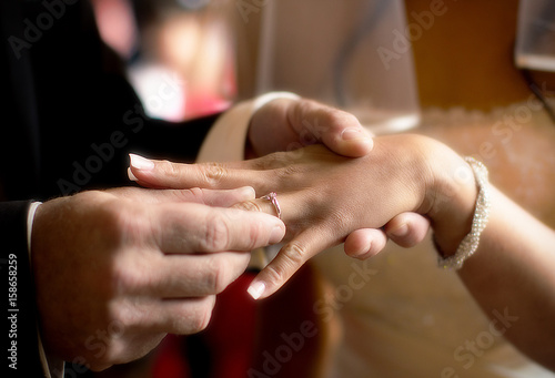 Close-up hands of bride and groom putting on a wedding rings