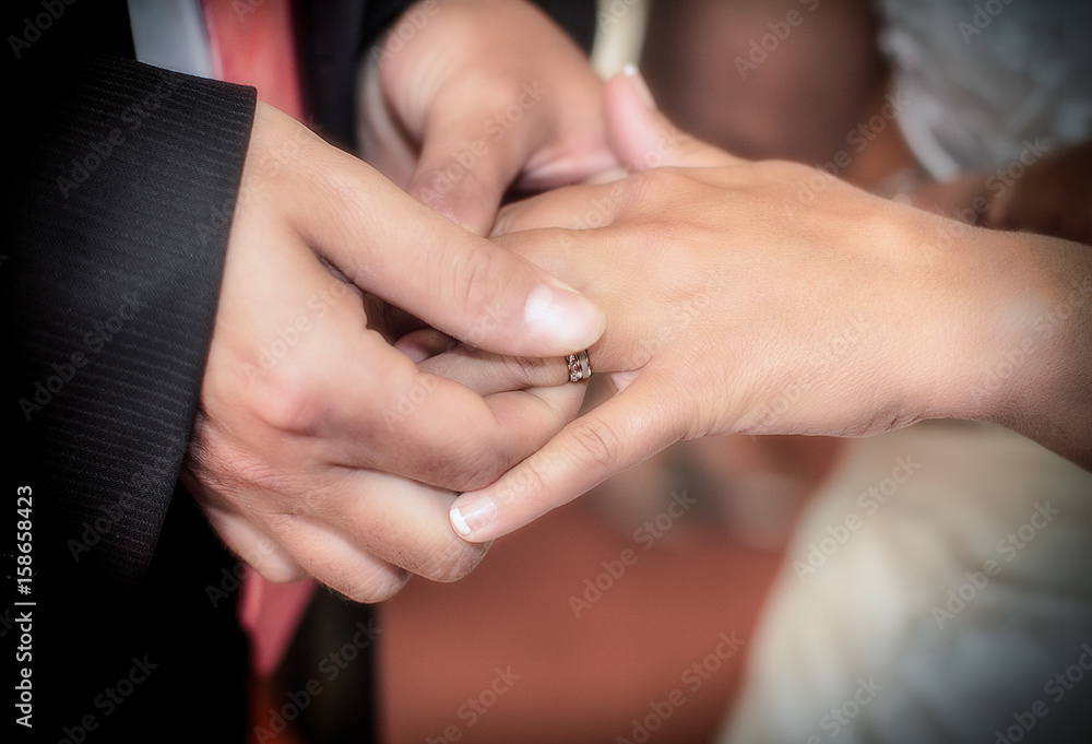 Close-up hands of bride and groom putting on a wedding rings