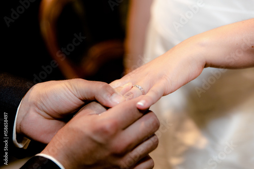 Close-up hands of bride and groom putting on a wedding rings © NizArt