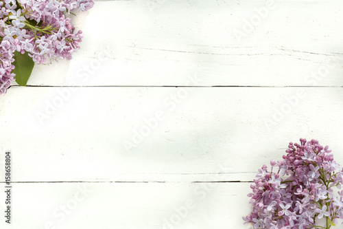 Bouquet of lilac flowers on white wooden background.