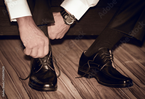 Groom wearing shoes on wedding day tying the laces