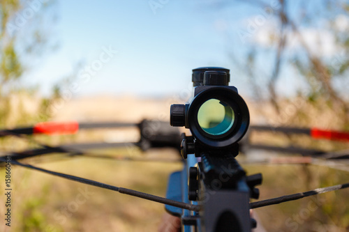 Foto Optical sight crossbow aiming from the first person on the background of the lake