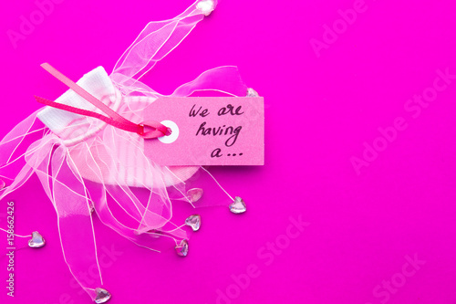 Baby Girl announcement - pink and white socks on pink background with label - we're having a girl
