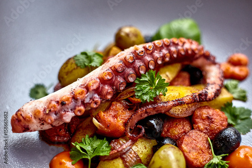 The process of eating the delicious grilled octopus. jukkumi bokkeum is korea traditional webfoot octopus with vegetable stir fry. photo