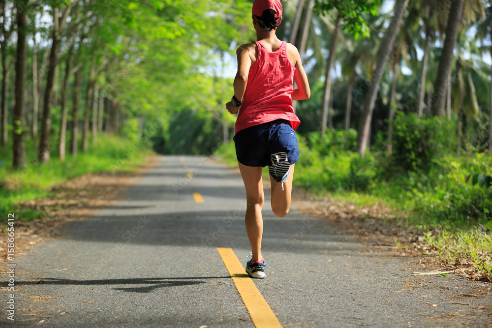 Young fitness woman running at morning tropical forest trail Young fitness woman running at morning tropical forest trail