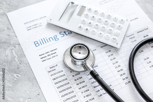 medical treatmant billing statement with stethoscope and calculator on stone background photo
