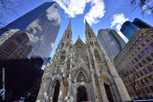 St. Patrick's Cathedral; frontal image in earl morning of St. Patrick's Cathedral with reflected light on spires and clouds over towers; contrast to new buildings