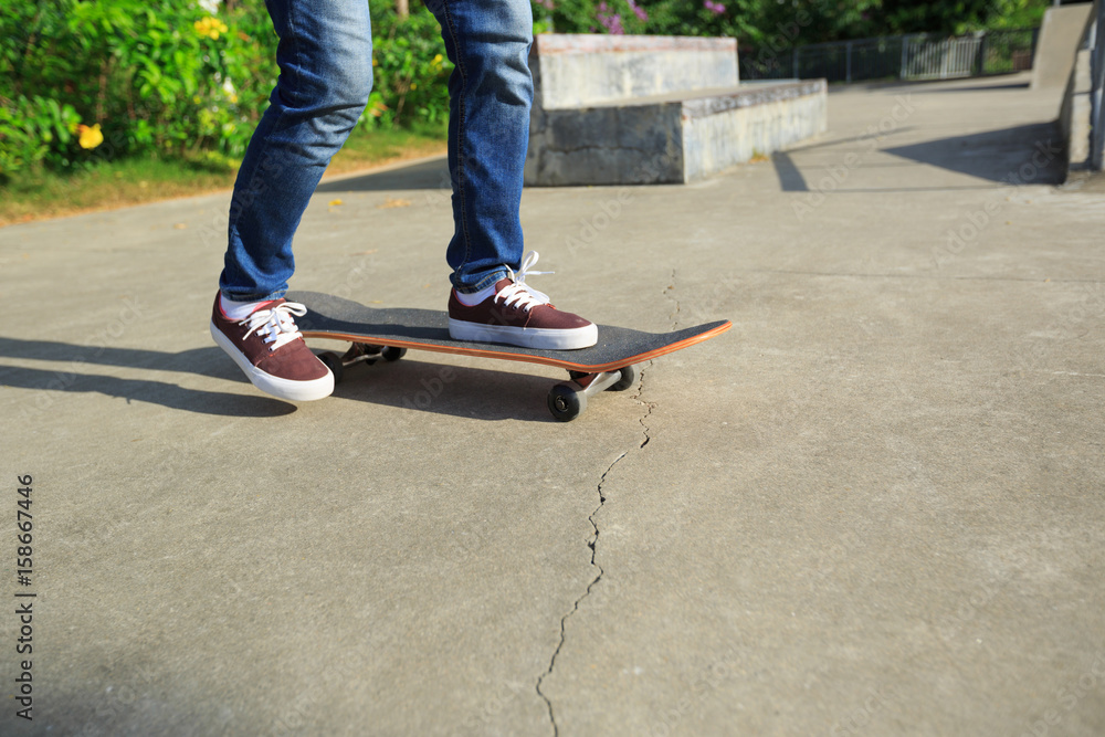 young skateboarder legs riding skateboard at skatepark young skateboarder legs riding skateboard at skatepark