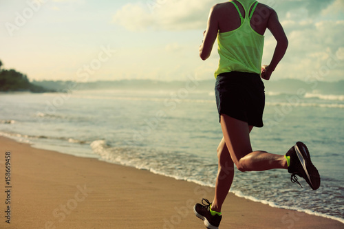 young fitness woman running on sunrise sandy beach