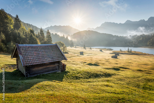 View over Geroldsee with wooden hut and Karwendel mountains at early morning in autumn, Bavaria, Germany