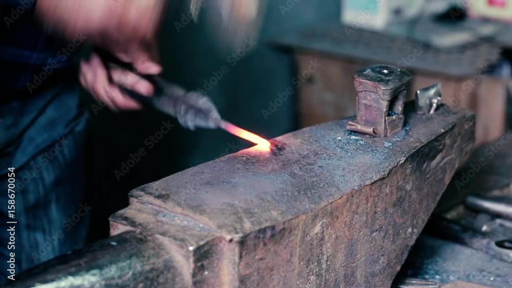 Blacksmith work. Blacksmith beats a piece of white hot metal with a hammer on an anvil. Antique Blacksmith Shop. The smith forges a horse horseshoe. Blacksmith work. Blacksmith beats a piece of white hot metal with a hammer on an anvil. Antique Blacksmith Shop. The smith forges a horse horseshoe.