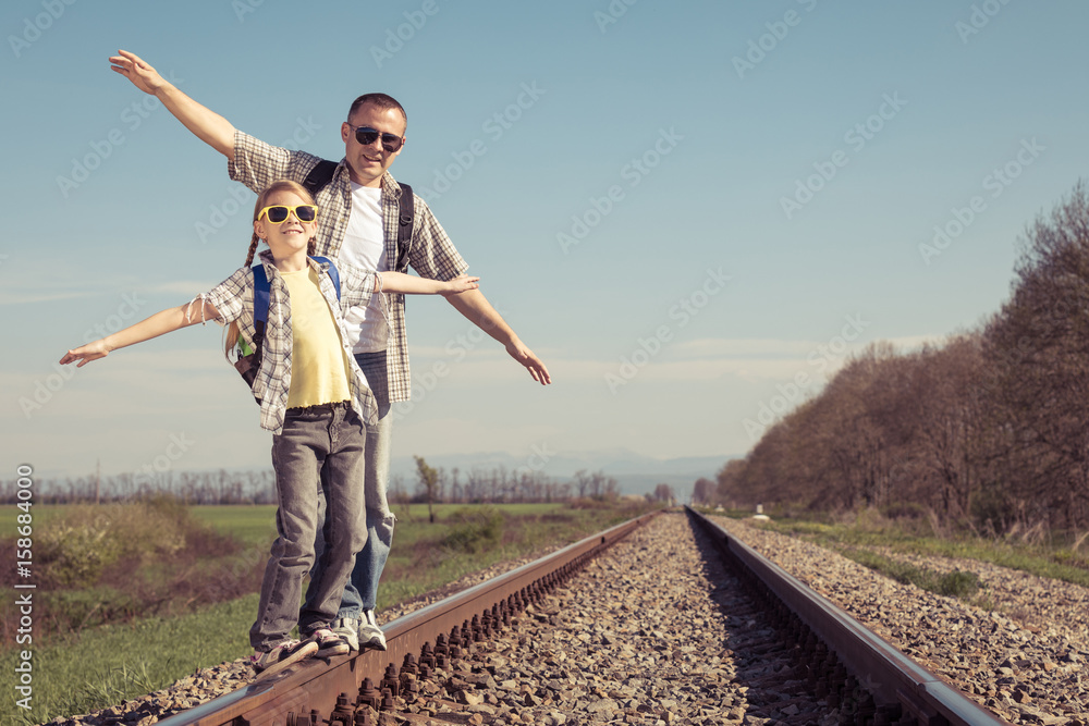 Father and daughter walking on the railway at the day time.