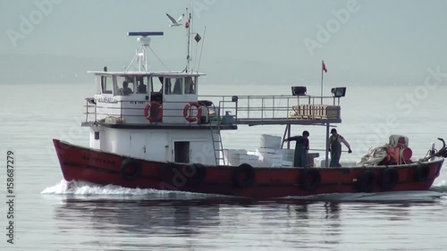 TUZLA, ISTANBUL, TURKEY – April 2, 2013: Fishing boat with working crew is passing by, seagulls fly around photo