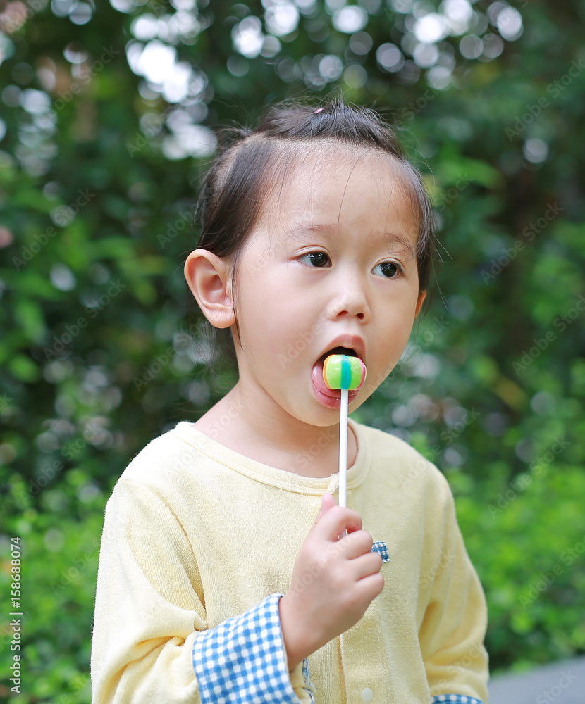 child girl enjoy eating lollipop candy in the park. child girl enjoy eating lollipop candy in the park.