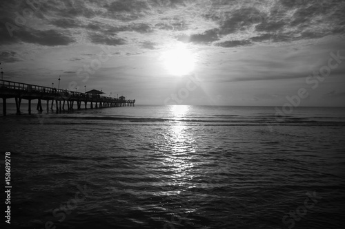 Sun over ocean with cloudy sky in black and white style