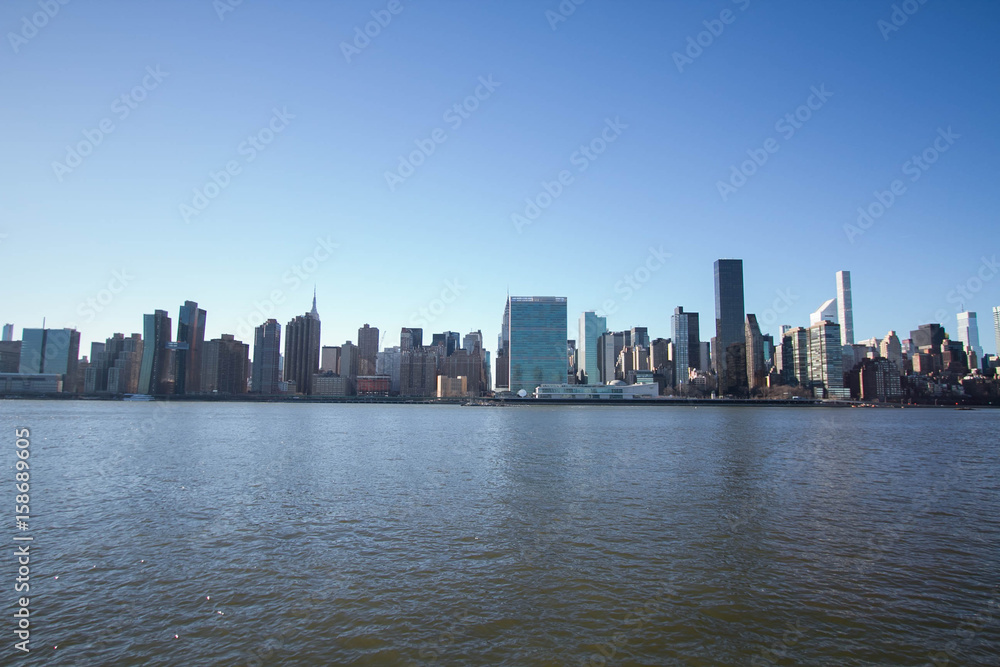 Cityscape of Manhattan over river with blue sky, New York