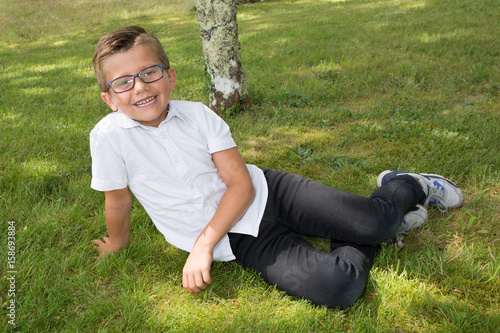 lying on grass young boy child funny with his glasses