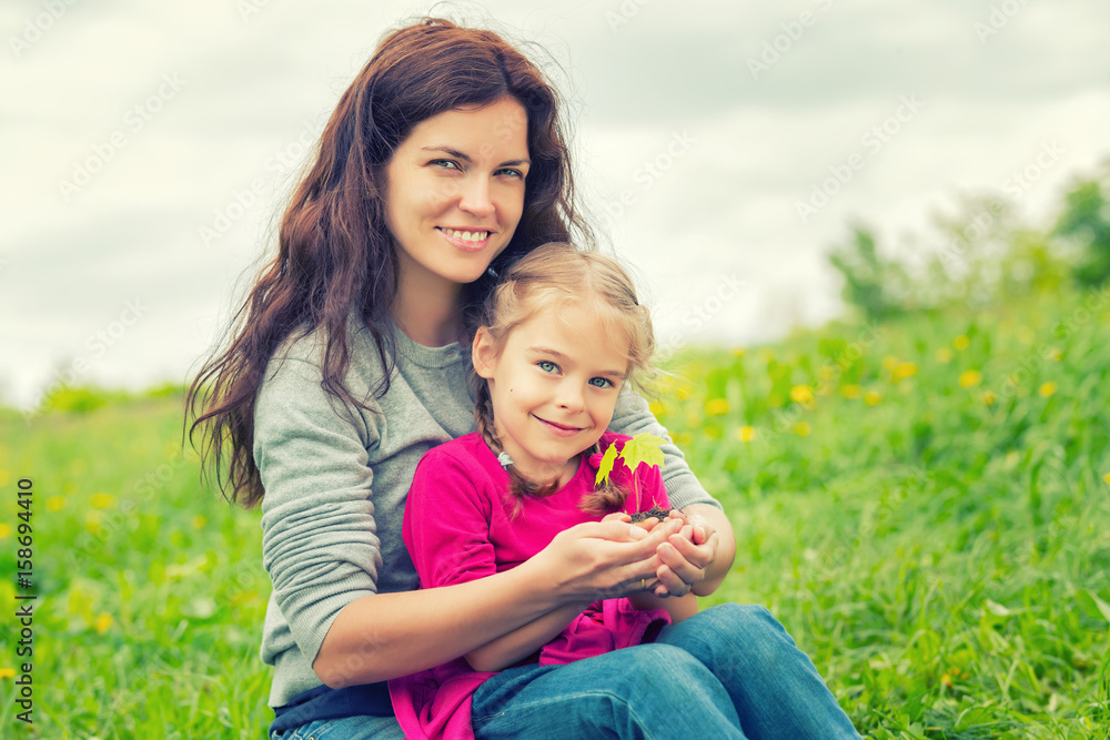 Mother and daughter holding little green plant in hands. Ecology concept Mother and daughter holding little green plant in hands. Ecology concept