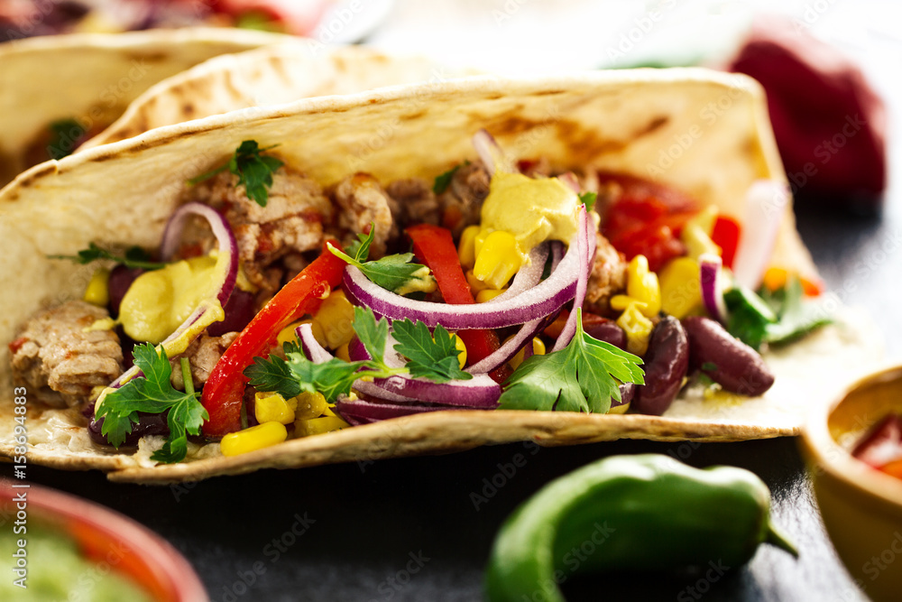 Beautiful tasty appetizing traditional mexican food tacos with meat and vegetables on black slate. Closeup. Beautiful tasty appetizing traditional mexican food tacos with meat and vegetables on black slate. Closeup.