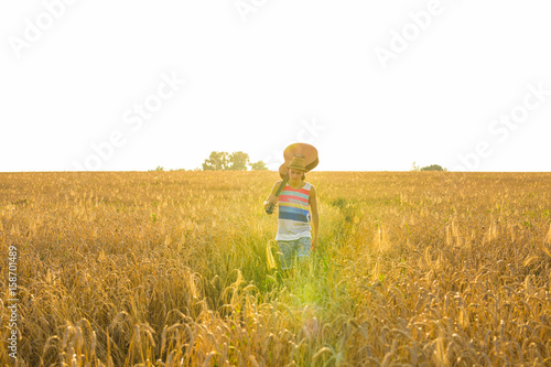 Young hipster man holding a guitar with a walking in nature, Relaxing in the field in a sunny day. © satura_