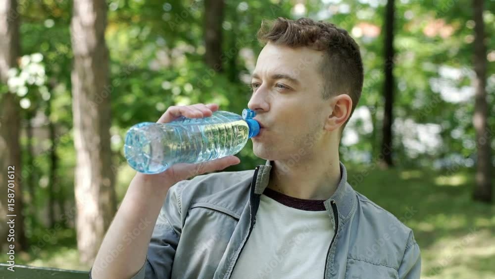 Relaxed man drinking water in the park and smiling to the camera, steadycam shot
Relaxed man drinking water in the park and smiling to the camera, steadycam shot