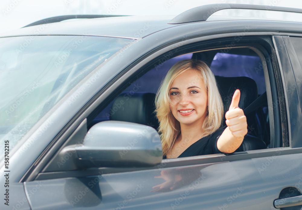 Beautiful young happy woman in car. Attractive blonde woman smiling.