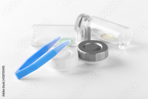Tweezers and container for contact lenses on white background