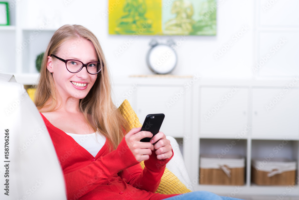 junge frau entspannt auf couch surft gücklich mit smartphone junge frau entspannt auf couch surft gücklich mit smartphone