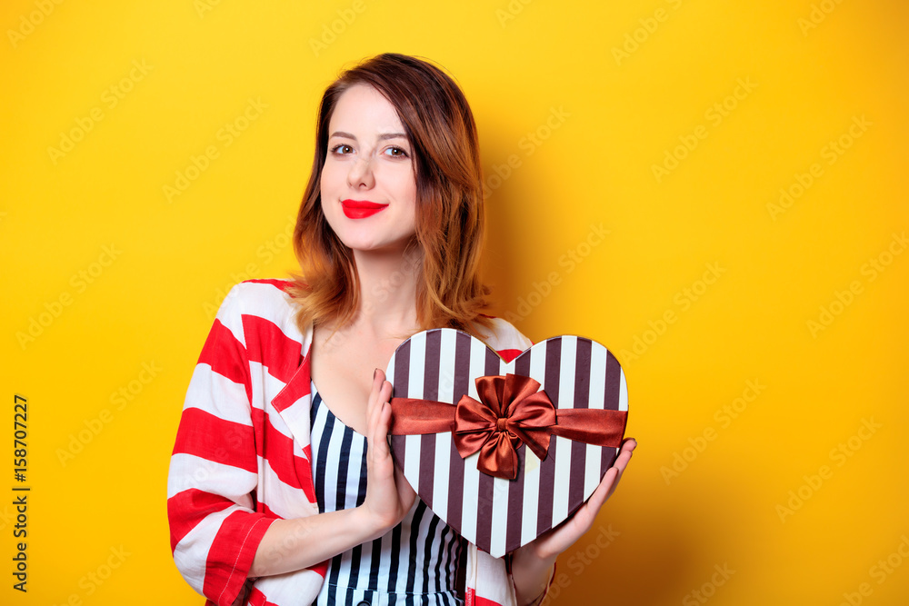 Woman with heart shape box on yellow background Woman with heart shape box on yellow background