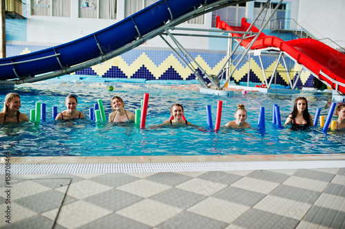 Fitness group of girls doing aerobical excercises in swimming pool at aqua park. Sport and leisure activities.