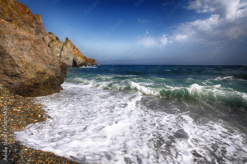 Sea waves crashing on the shore and flowing above seashore pebbles