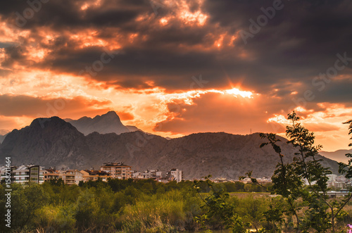 Fantastic colorful sunset and bloom malva erecta at the foot of Antalya mountains. Dramatic overcast sky with clouds. Antalya, Turkey, Middle East