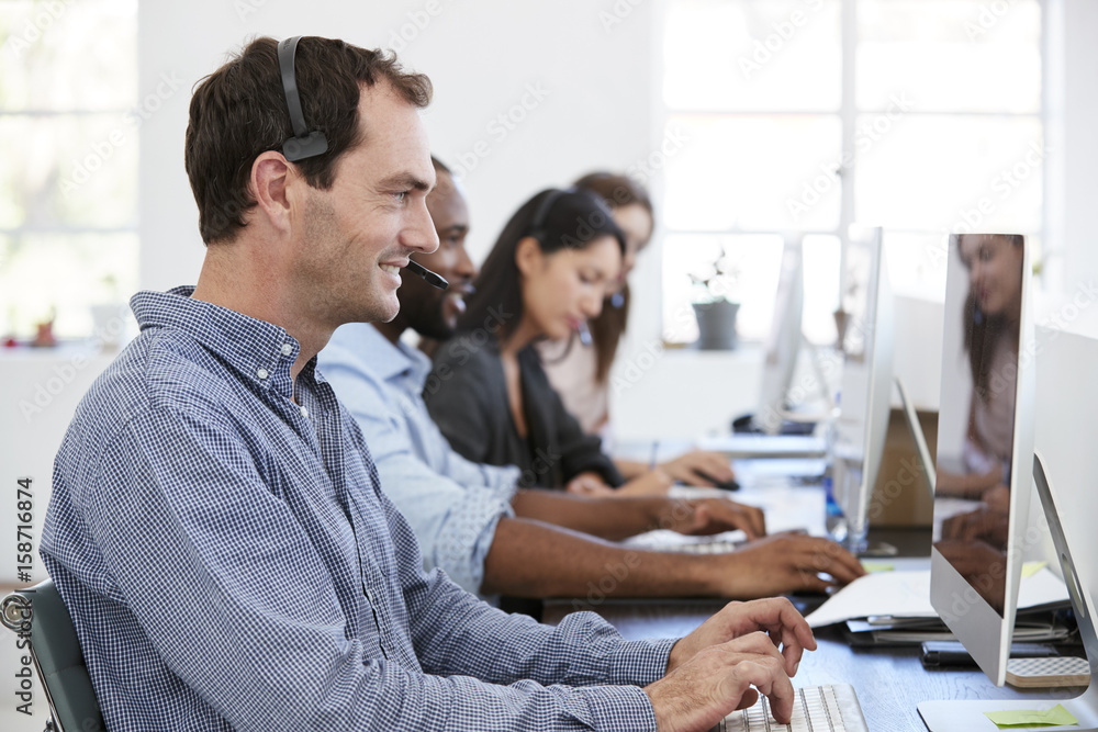 Obraz premium Young white man with headset working at computer in office