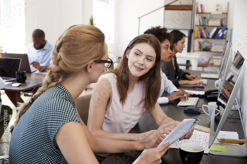 Woman training new female employee in an open plan office © Monkey Business