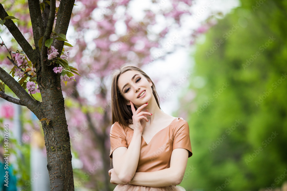 Young pretty woman smelling flowers in blooming sakura garden Young pretty woman smelling flowers in blooming sakura garden