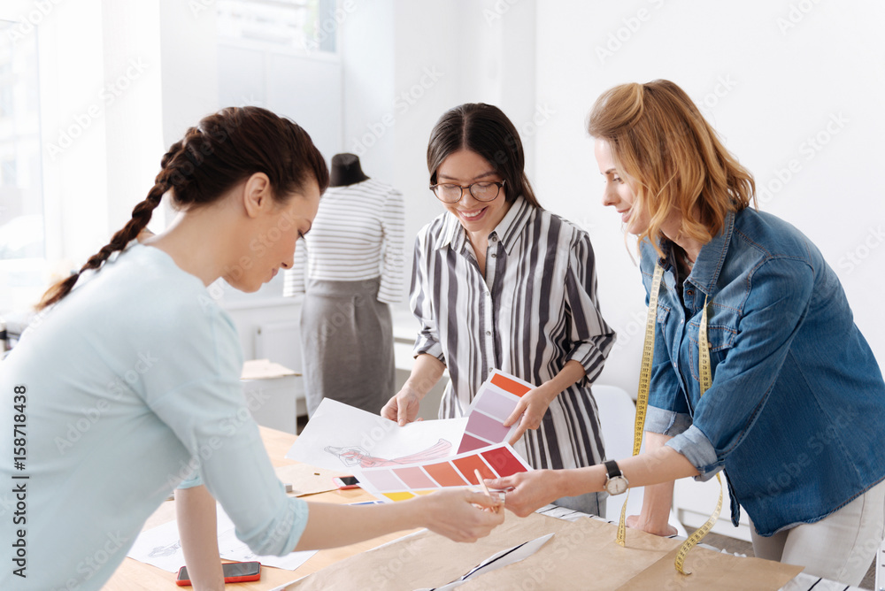 Three cheerful workers discussing new outfit Three cheerful workers discussing new outfit