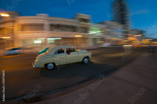 Vintage American car serving as taxi passes in a blur along the Malecon in Central Havana at dusk. Panning technique, slow shutter speed. © lazyllama