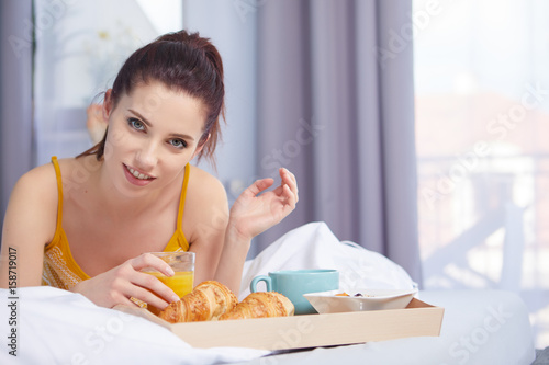 Young beautiful woman having breakfast in bed.