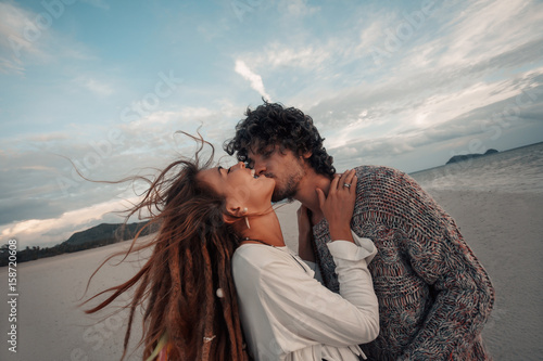 beautiful young couple kissing on beach at sunset
