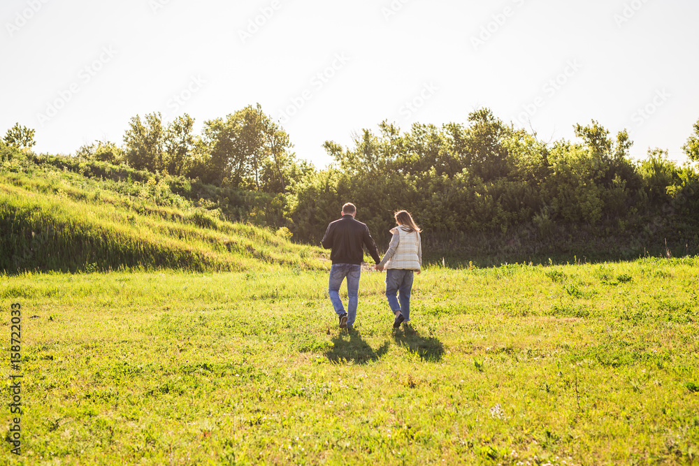 Man and woman holding hands and walking on nature, back view Man and woman holding hands and walking on nature, back view