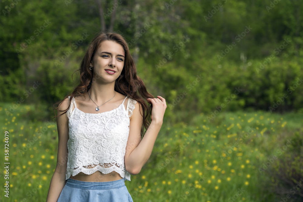 Portrait of a girl with long hair against the background of grass and trees Portrait of a girl with long hair against the background of grass and trees