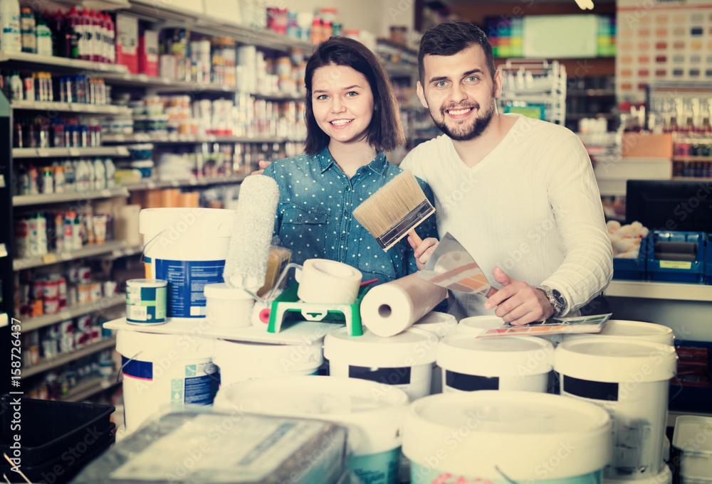 Fototapeta premium Couple purchasing tools for house improvements in paint supplies store
