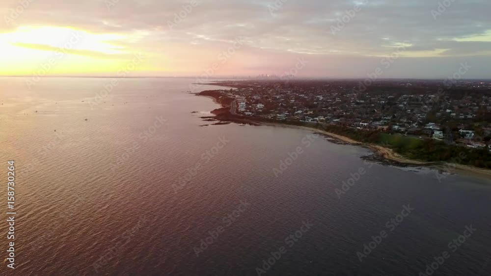 Aerial view of of Melbourne above beach at sunset while moving foward Aerial view of of Melbourne above beach at sunset while moving foward
