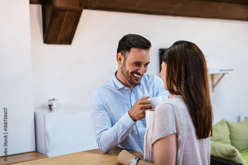 Beautiful young couple is talking and smiling while drinking coffee Beautiful young couple is talking and smiling while drinking coffee