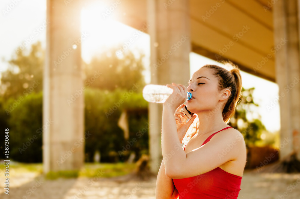 Beautiful young women drinking water after running Beautiful young women drinking water after running