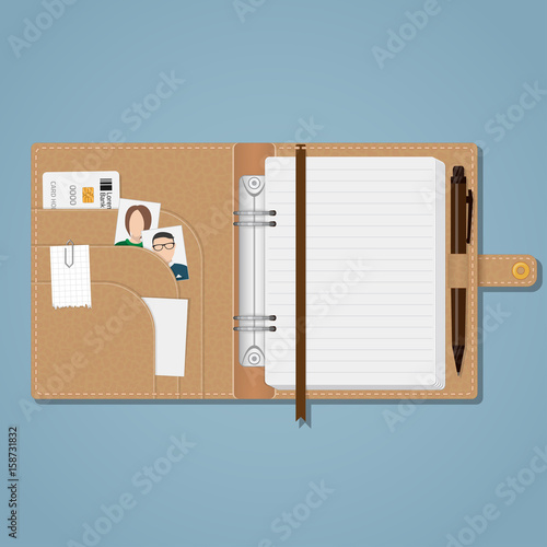 An open brown leather notebook on a rivet with white sheets in a line, a bookmark, pockets on the cover and a pen holder with a pen. In the cells a credit card, a photo of relatives.