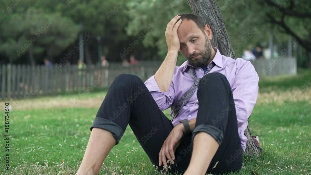 Portrait of sad, tired businessman sitting on grass in park
Portrait of sad, tired businessman sitting on grass in park
