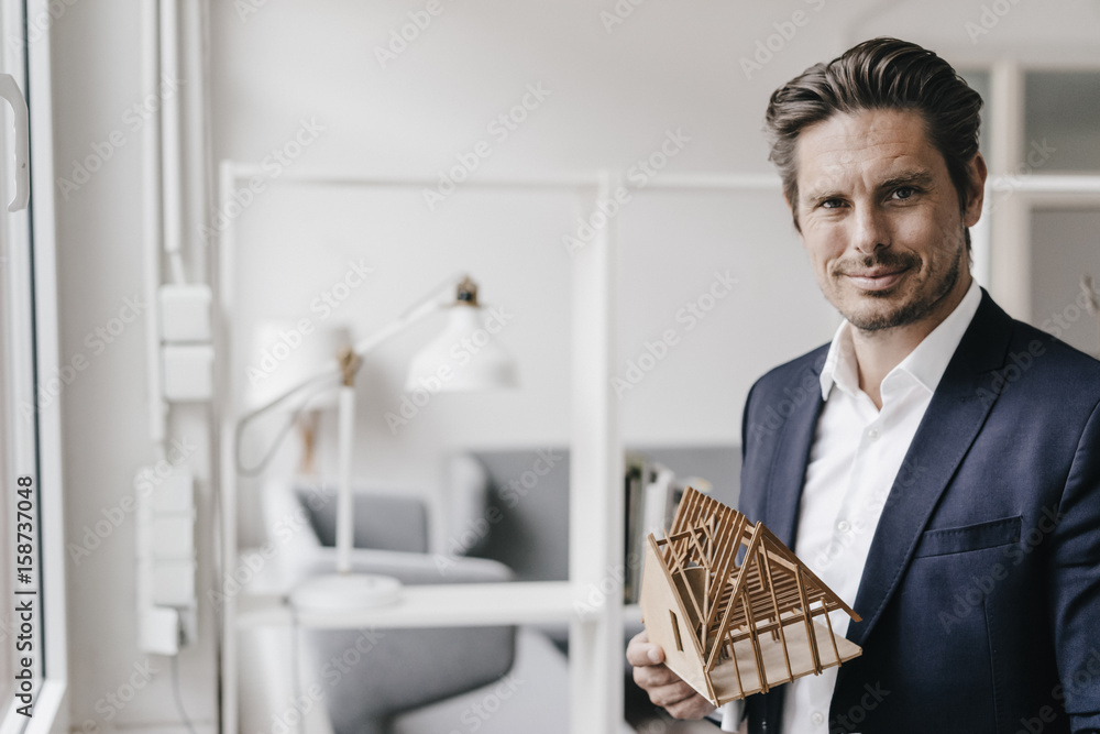 Confident architect holding architectural model
